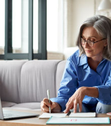 Woman writing with laptop open